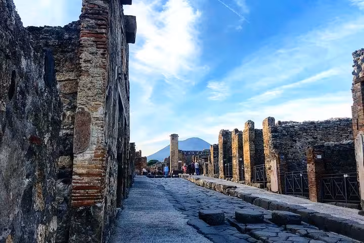 Explore ancient Pompeii streets with stunning views of Mount Vesuvius on a guided tour from Sorrento Coast.