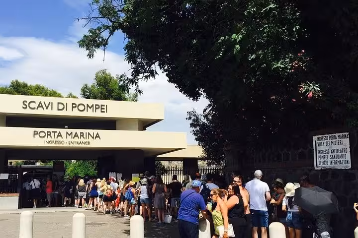 Visitors queue at Pompeii's Porta Marina entrance, ready for a guided tour from Sorrento Coast under sunny skies.