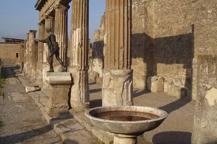 Ancient ruins with statues and columns at Pompeii, highlighting historical architecture on a full-day tour.
