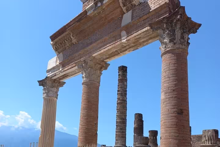 Ancient Roman columns of Pompeii with Mount Vesuvius in the background, perfect for historical tour enthusiasts.