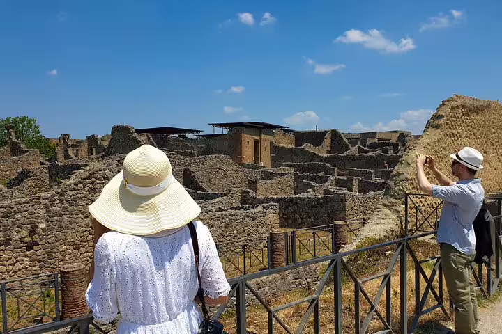 Travelers capture photos of ancient ruins at Pompeii, experiencing a historic day trip from Naples.