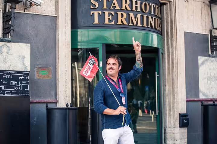 Tour guide holding a flag outside Starhotel Terminus, ready for the Pompeii and Mt. Vesuvius day trip from Naples.