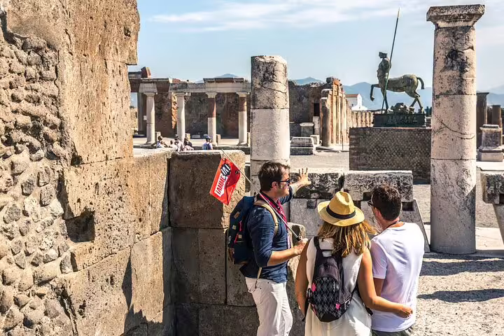 Tourists explore ancient ruins guided by an expert on the Skip The Line Pompeii Tour from Sorrento.