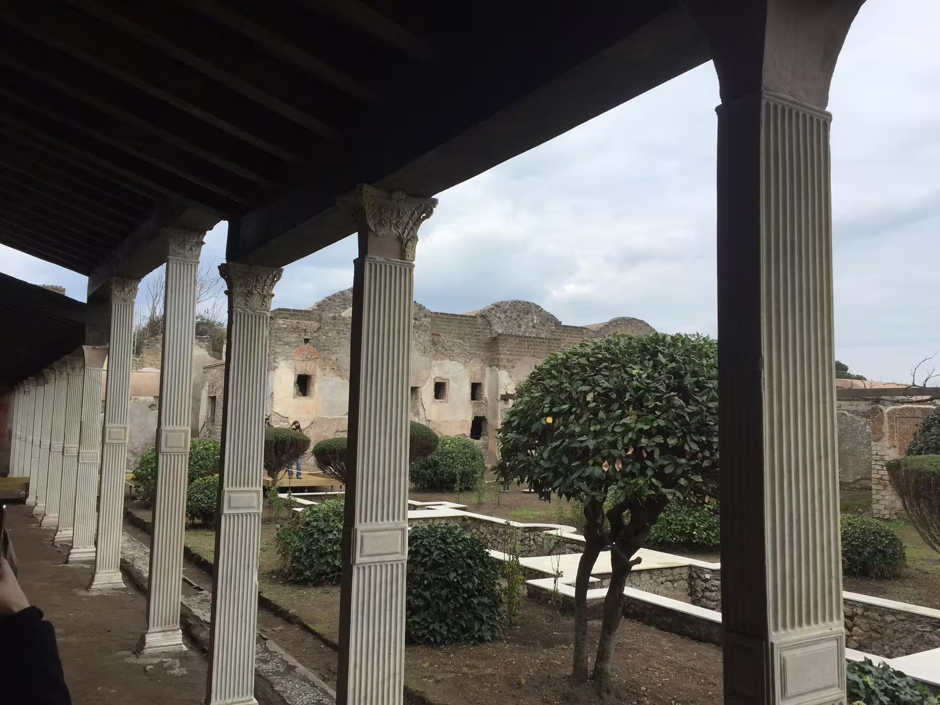 Pompeii peristyle garden with fluted columns and shrubs, part of a low cost Pompeii tour from Naples