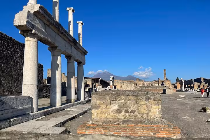 Columns and ruins stand under a clear blue sky in Pompeii, offering a glimpse into the grandeur of ancient Roman architecture.