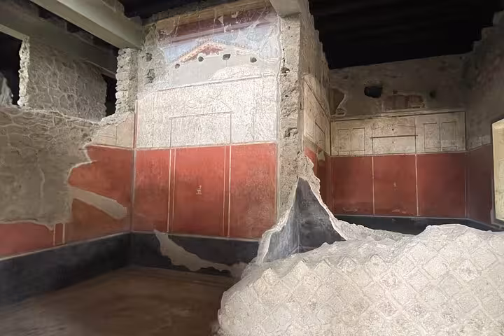Ruins of a vibrant red and white frescoed room in Pompeii, showcasing ancient Roman art on the Amalfi Coast tour.