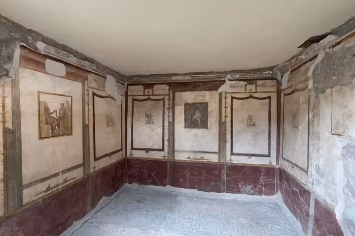 Elegant frescoes with detailed Roman art in a Pompeii room, highlighting the historical richness of the site.