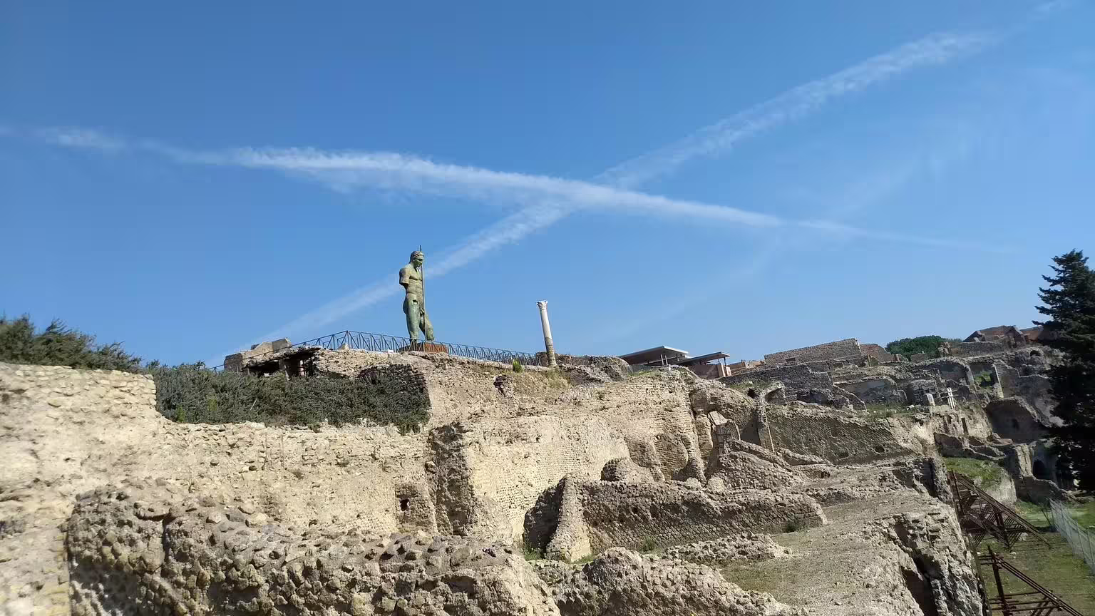 Pompeii archaeological ruins with ancient statue under blue sky on Naples to Amalfi Coast group tour