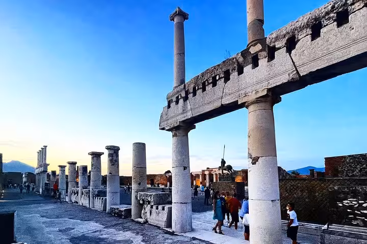 Ancient ruins of Pompeii with towering columns at sunset, offering a glimpse into history on an Amalfi Coast day tour.