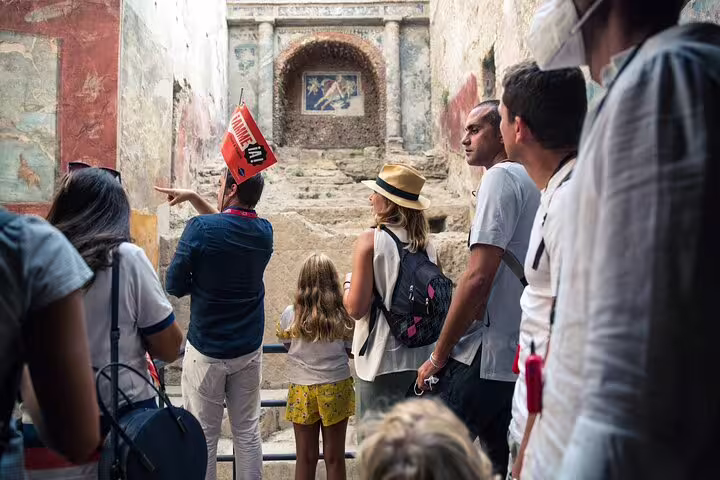 Guided group admires detailed frescoes inside Pompeii ruins, emphasizing cultural heritage and archaeological discovery.