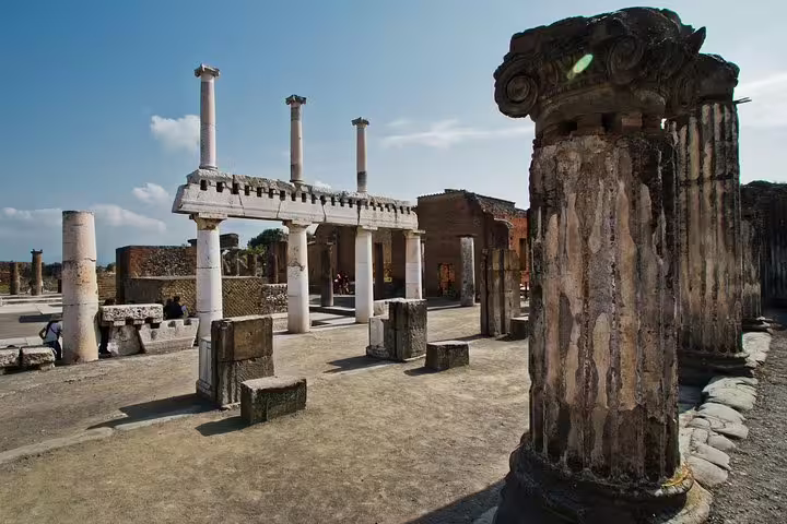 Explore ancient Pompeii ruins on a guided tour from Naples, featuring impressive Roman columns and historic architecture.