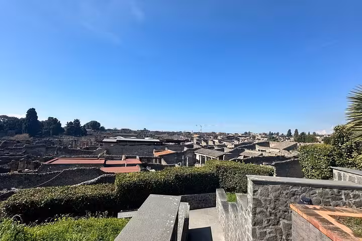 Panoramic view of Pompeii ruins under a clear blue sky, highlighting key sites on a guided tour with no waiting in line.