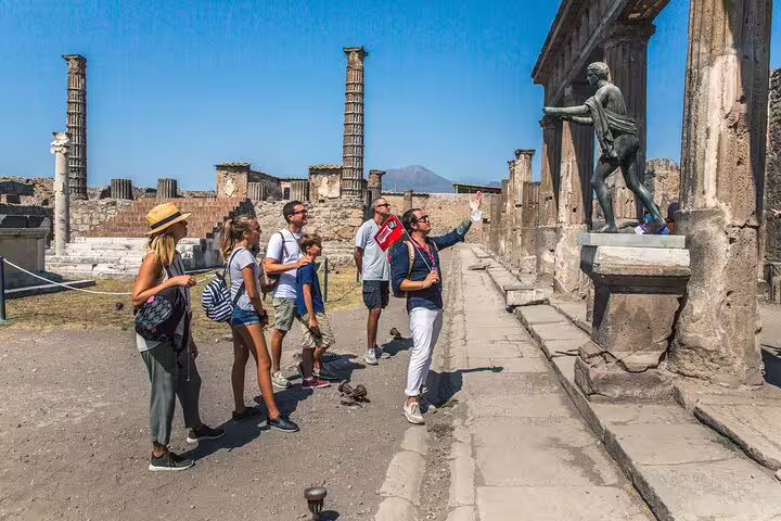 Visitors admiring ancient statues during guided tour of Pompeii ruins near Vesuvius.