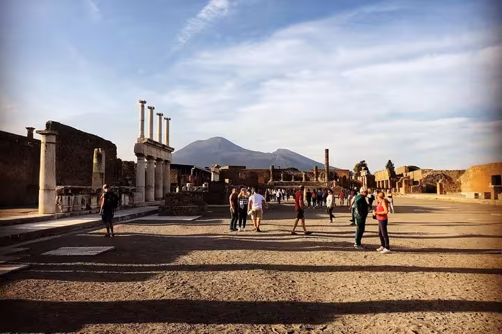 Tourists explore ancient Pompeii ruins with Mount Vesuvius in the background, capturing a glimpse of history and nature.