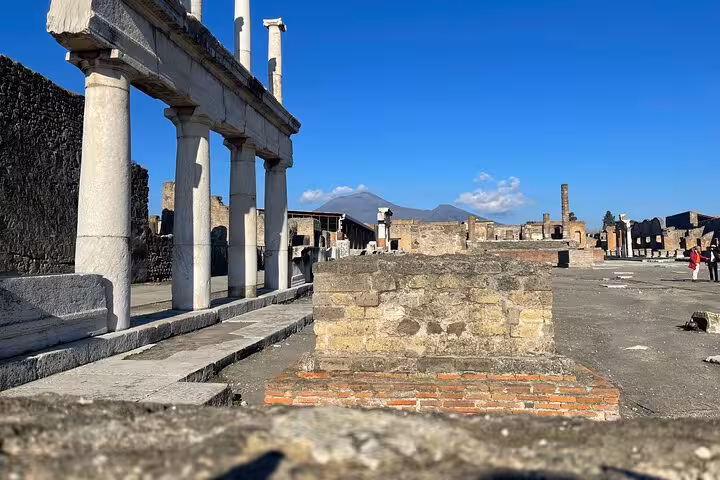 View of Pompeii ruins with Mount Vesuvius in the background, part of the exclusive guided tour experience.
