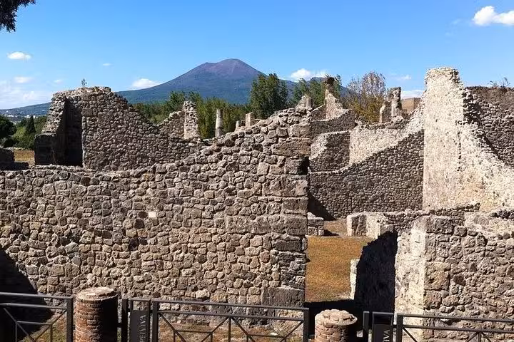 View of Pompeii's stone ruins with Mount Vesuvius in the distance, part of our exclusive Naples tour package.