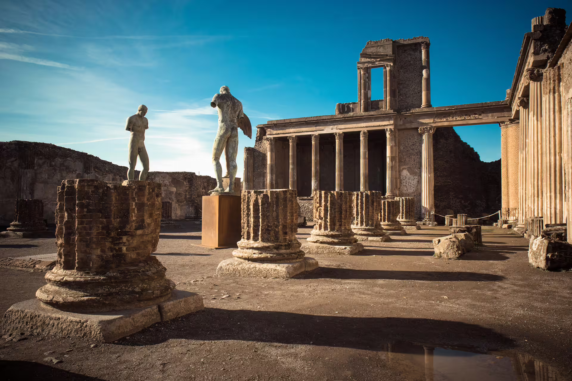 Pompeii ruins with Roman statues and temple columns, highlight of Naples group tour with wine tasting