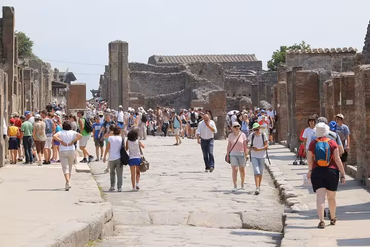Tourists wander through bustling Pompeii ruins, ideal for small group tours exploring history and culture.