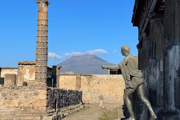 Ancient Pompeii ruins with statue and Mt. Vesuvius view on guided tour from Amalfi Coast.