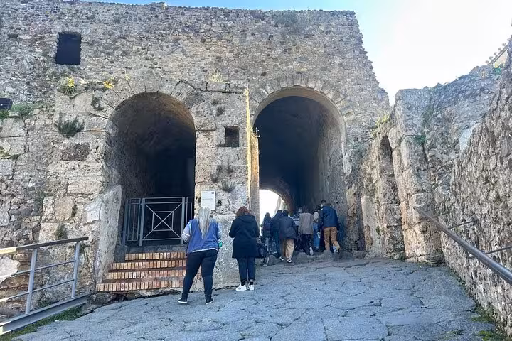Visitors entering Pompeii through ancient stone arches on a Skip-the-Line Entry Small Group Guided Tour.