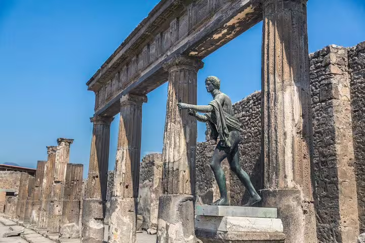 Statue amidst the historic columns of Pompeii, showcasing ancient Roman architecture.