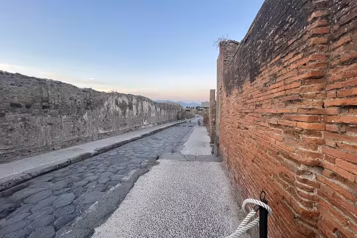 Sunset light casts a warm glow on the cobblestone streets of Pompeii, offering a glimpse into ancient Roman life.