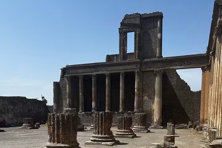 Ancient columns and ruins of a historic Pompeii temple under clear skies, highlighting the archaeological significance.