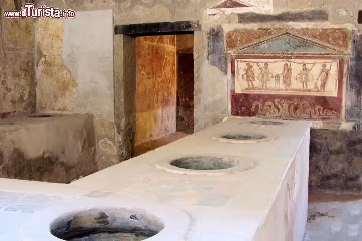 Ancient thermopolium food counter and frescoes in the archaeological ruins of Pompeii on a guided shore excursion