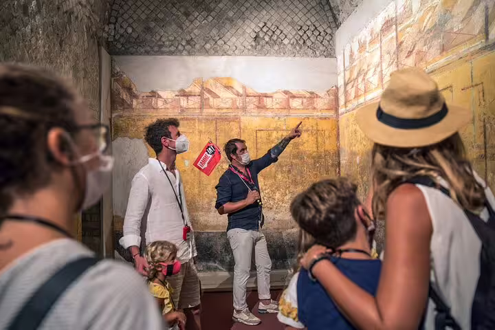 Tour guide explains ancient frescoes to a group on a skip-the-line Pompeii tour from Sorrento.