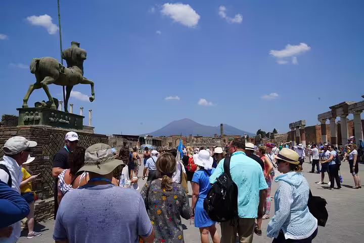 Visitors admire statue and view of Mount Vesuvius on a skip-the-line Pompeii tour from Sorrento.