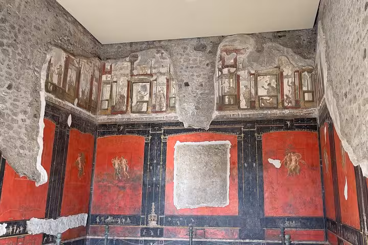 Explore ancient Pompeii frescoes with vivid red hues and intricate designs on the Pompeii & Vesuvius tour from Positano.