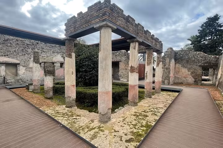 Explore ancient ruins with columns and greenery on a Pompeii and Vesuvius small group tour from Sorrento.