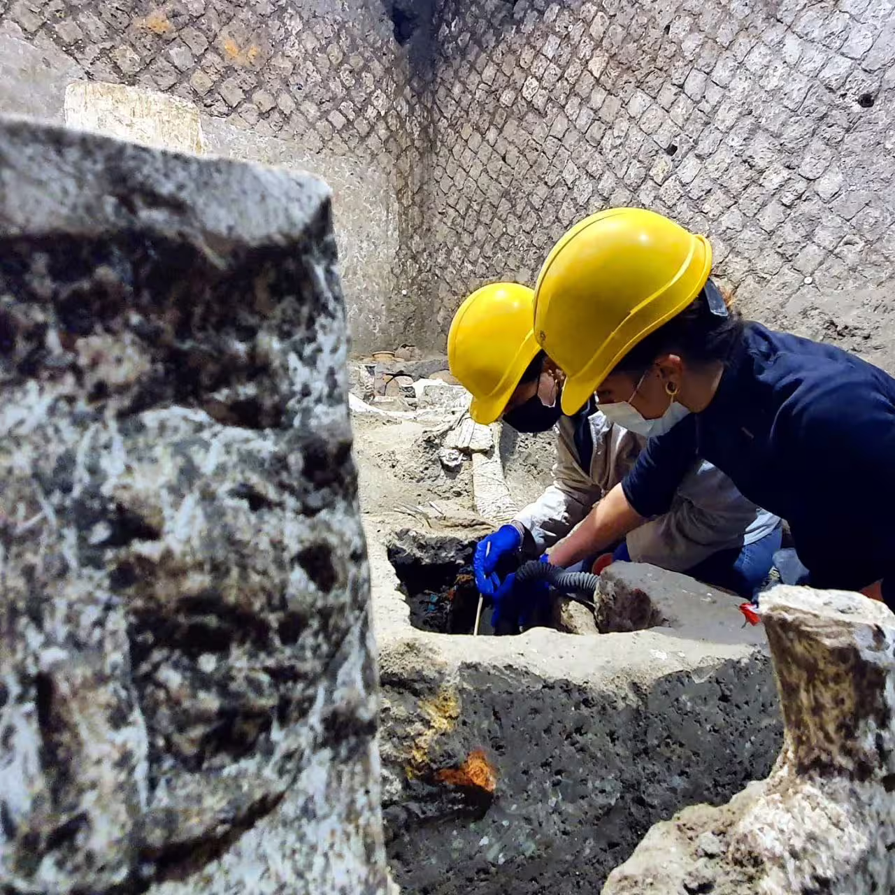 Archaeologists excavating at Pompeii with safety helmets, highlighting ongoing discoveries on Naples to Pompeii tour