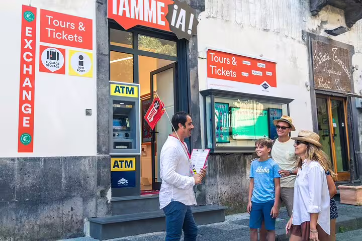 Family interacting with a guide at a tour and ticket office in Sorrento, ready for a Pompeii and Vesuvius adventure.