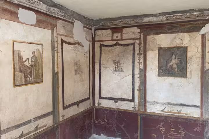 Intricate wall frescoes in a Pompeii villa room highlight Roman artistic craftsmanship, available on a skip-the-line tour.