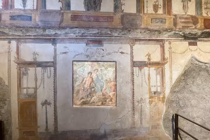 Intricate wall paintings in Pompeii, illustrating ancient art on the Pompeii & Vesuvius tour with wine tasting.