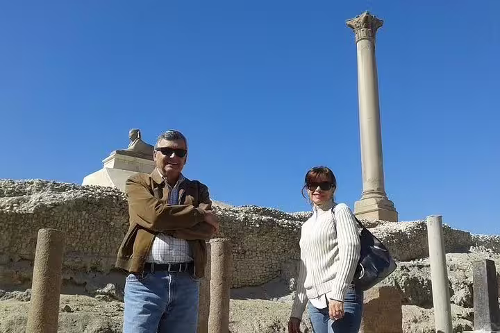Travelers at Pompey’s Pillar ruins in Alexandria, key sightseeing stop on a private day tour from Cairo