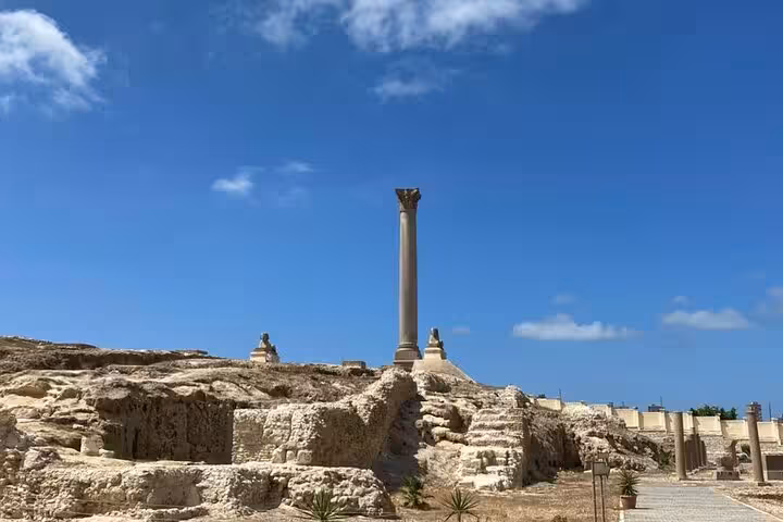 Pompeys Pillar ruins under blue sky in Alexandria on private historical guided day tour from Cairo