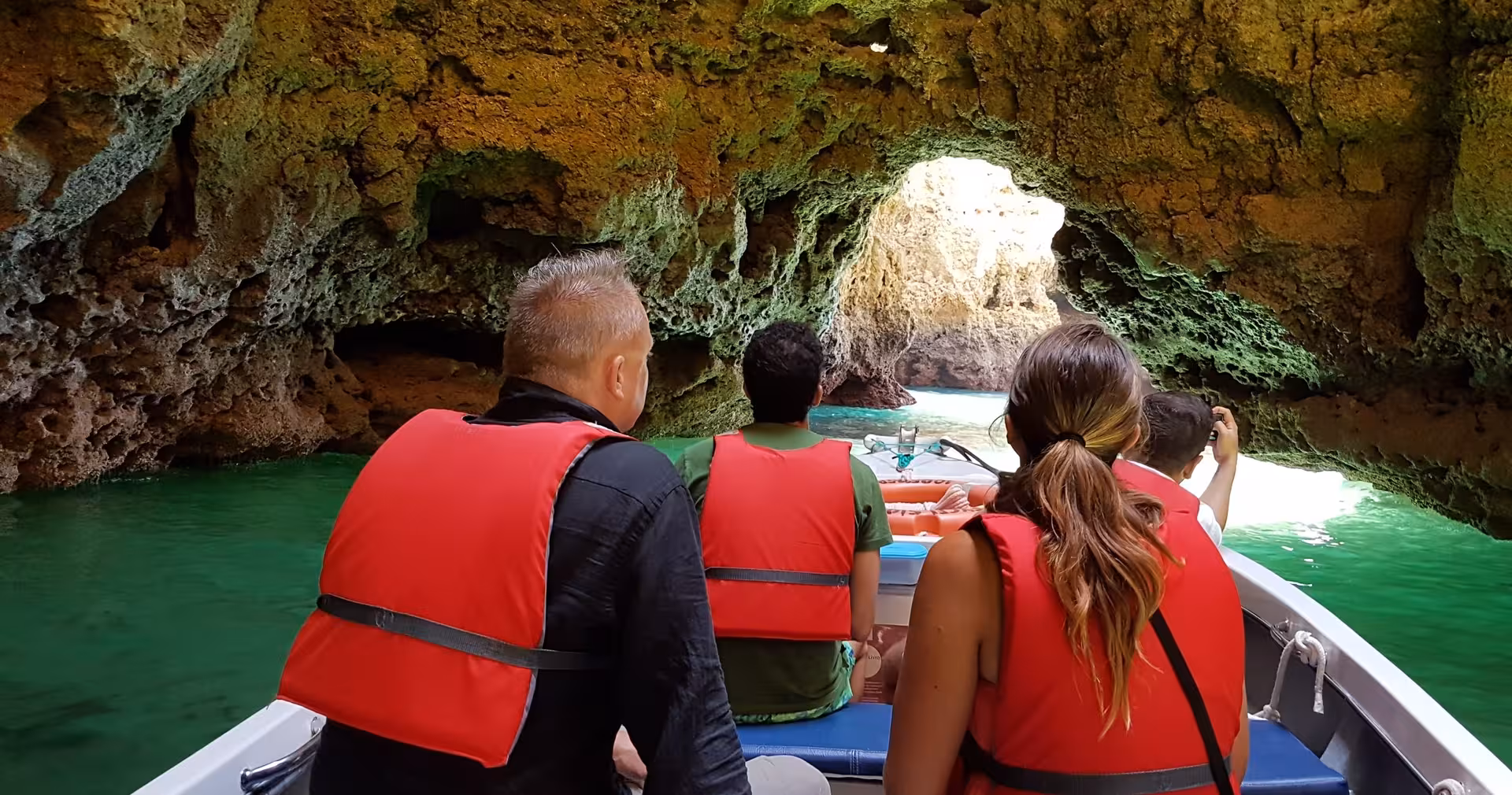 Group exploring Ponta da Piedade sea caves by boat in Lagos, Algarve, gliding through emerald water beneath rocky arches