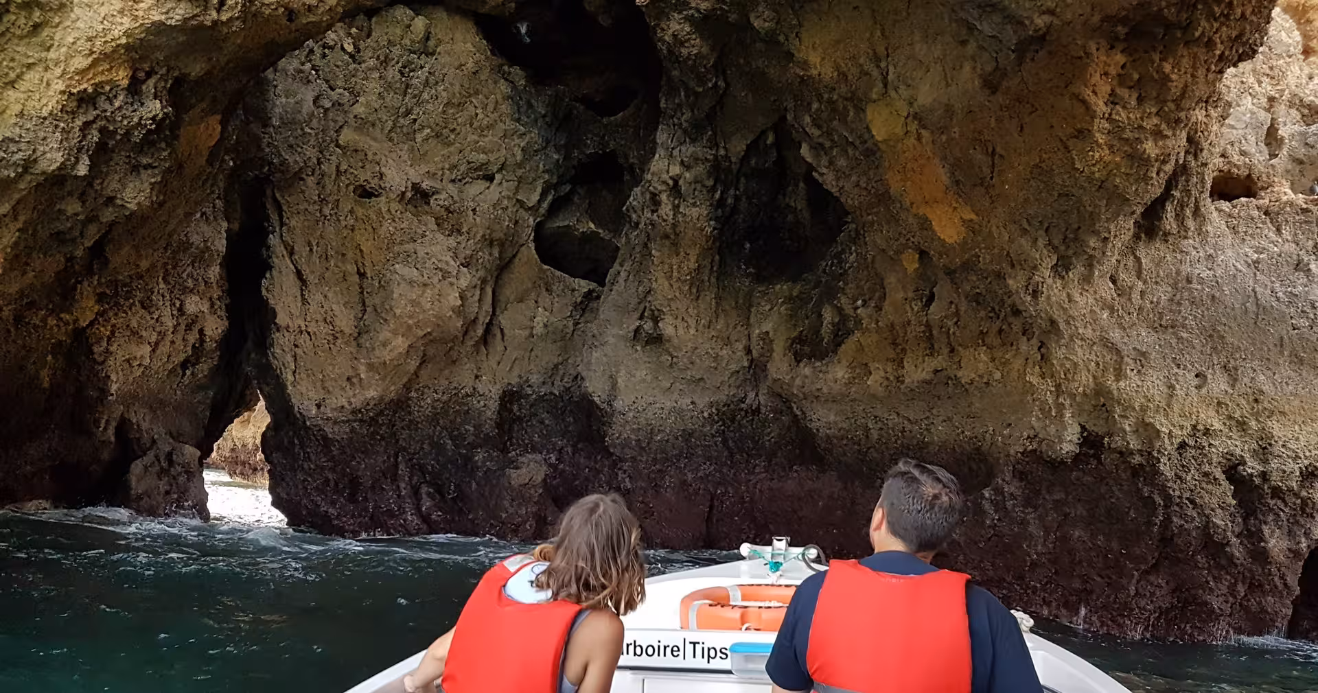 Small boat tour to Ponta da Piedade caves in Lagos, Portugal, with passengers in life jackets entering a dramatic sea grotto