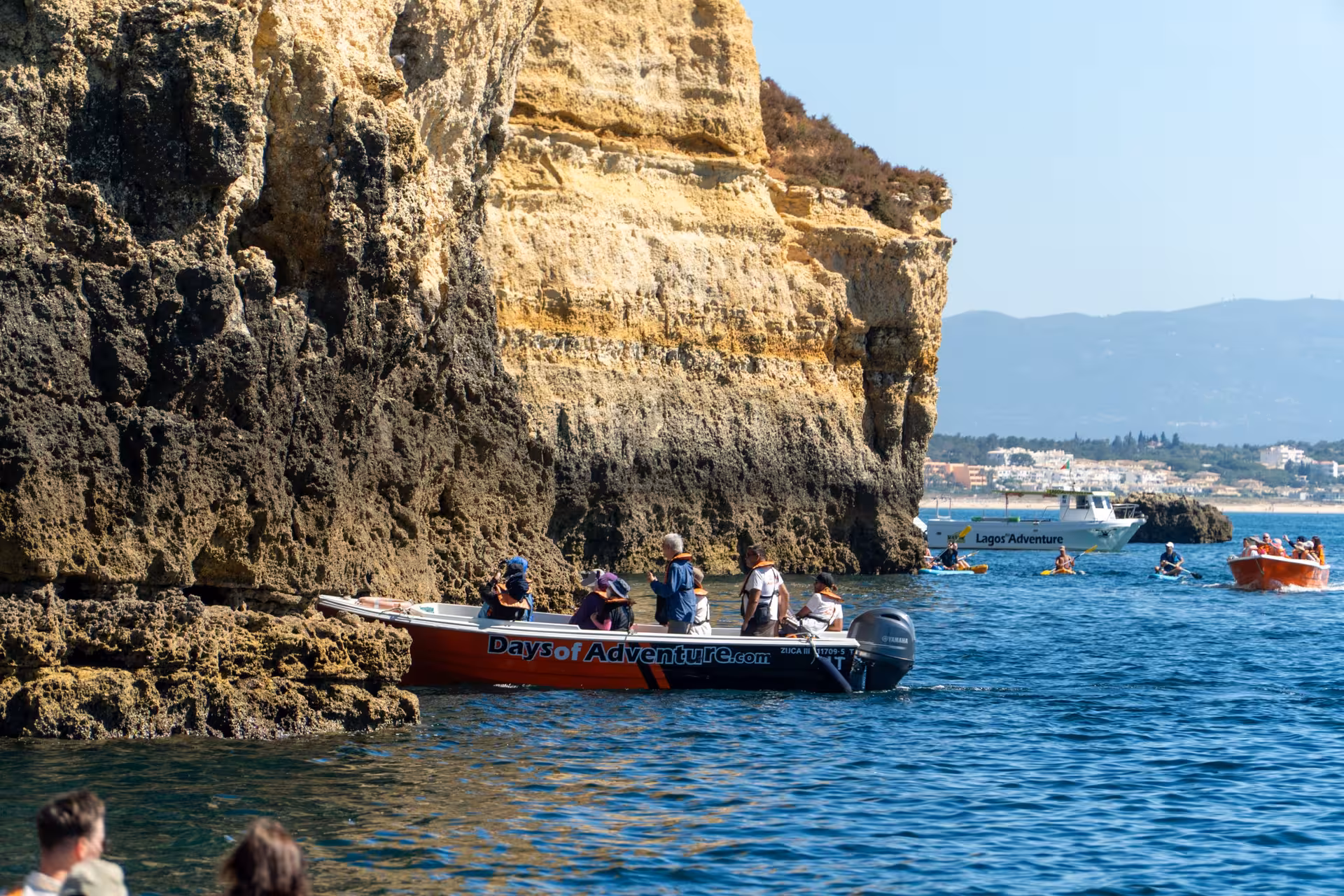 Tour boat navigating tourists through dramatic Ponta da Piedade sea caves and rugged rock formations in Lagos Algarve
