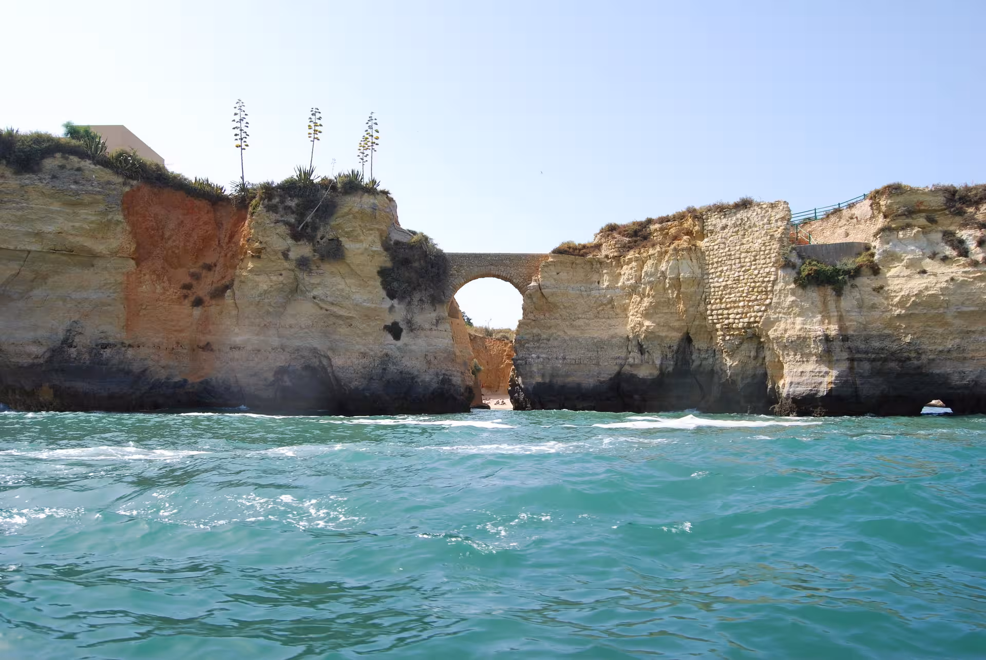 View from boat of turquoise Atlantic waves and stone arch bridge between dramatic cliffs near Ponta da Piedade, Lagos Algarve
