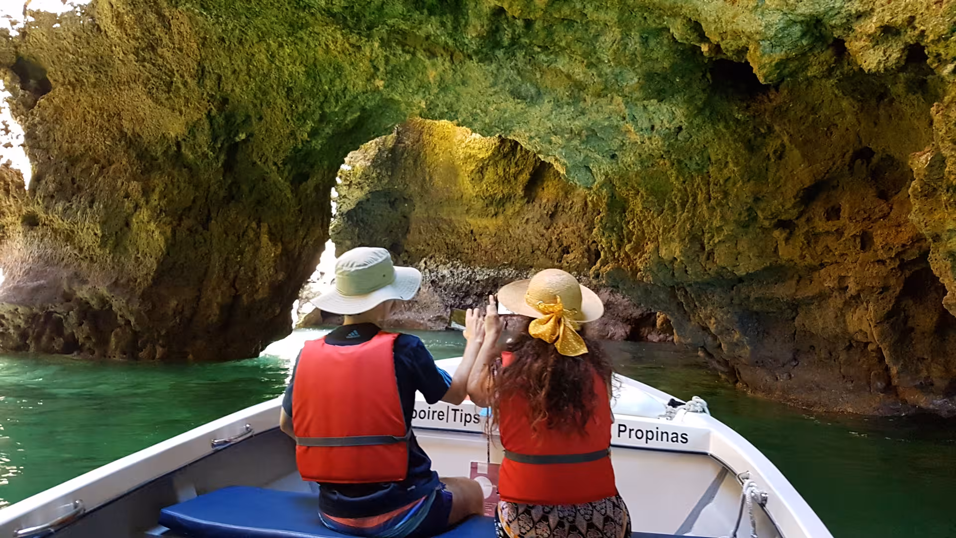 Couple in hats and life jackets enjoy a Lagos boat trip beneath dramatic Ponta da Piedade rock arches and turquoise water