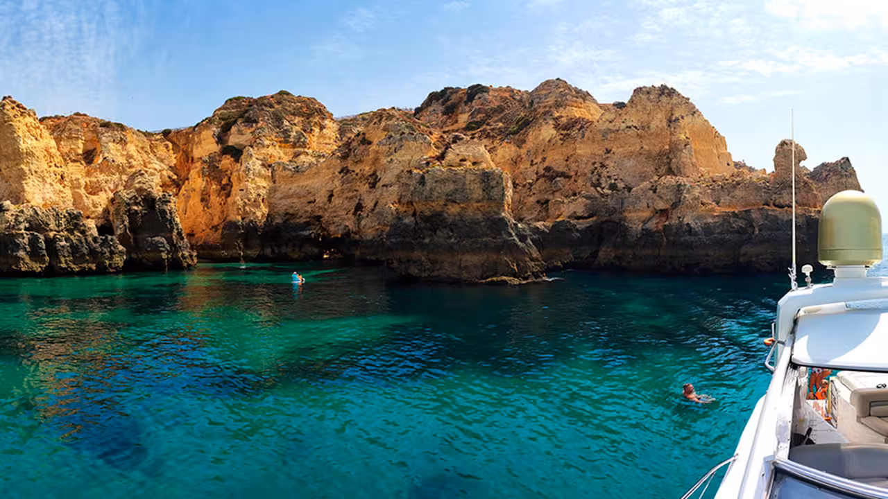 Swimmers in a sheltered cove beneath Ponta da Piedade cliffs, Lagos Algarve, during a full-day boat cruise