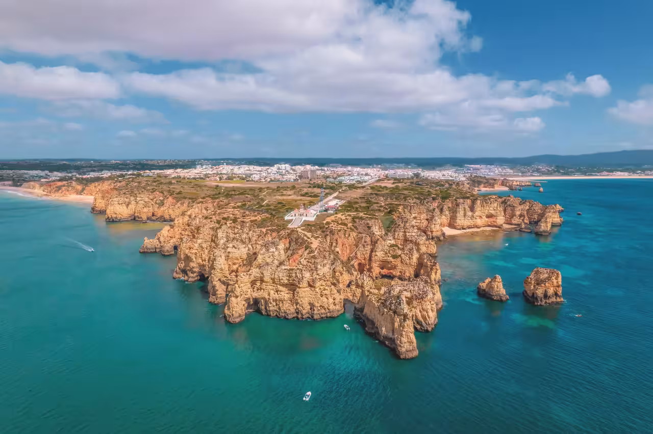 Aerial view of Ponta da Piedade golden limestone cliffs and sea caves surrounded by turquoise Atlantic waters near Lagos Algarve Portugal