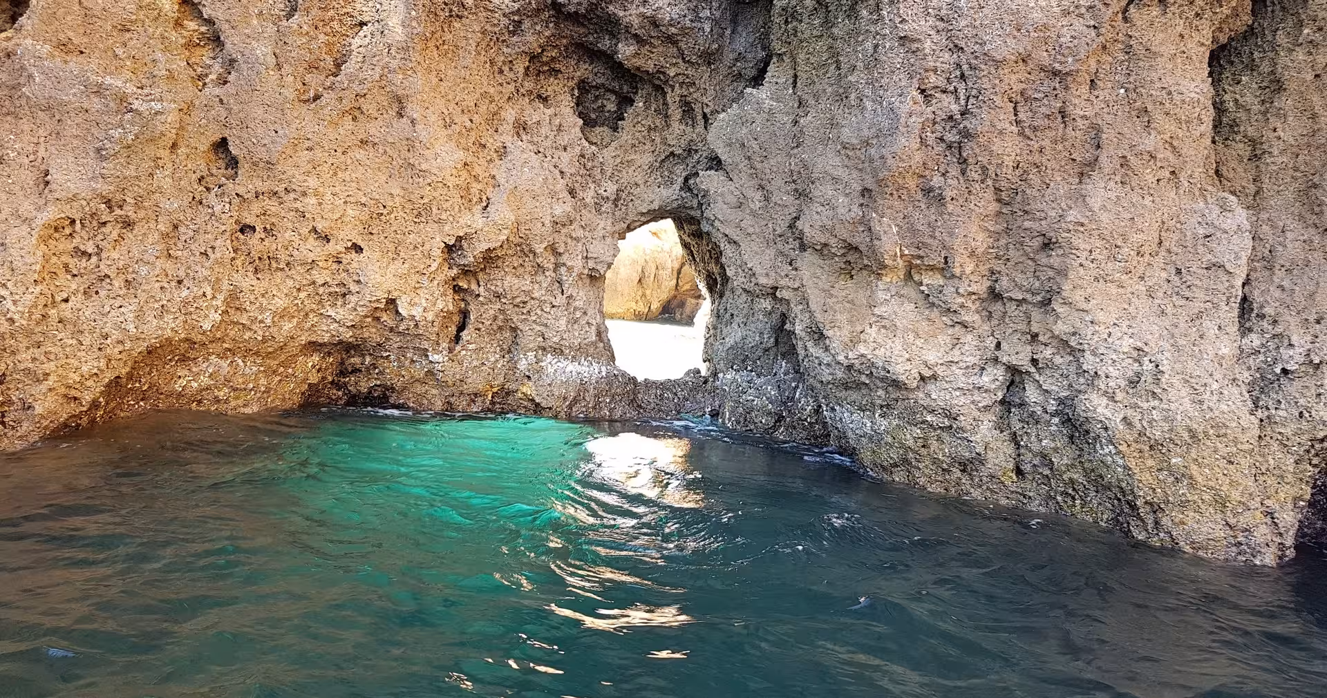 Emerald water and natural rock tunnel at Ponta da Piedade in Lagos, explored on a guided Algarve coastal boat tour