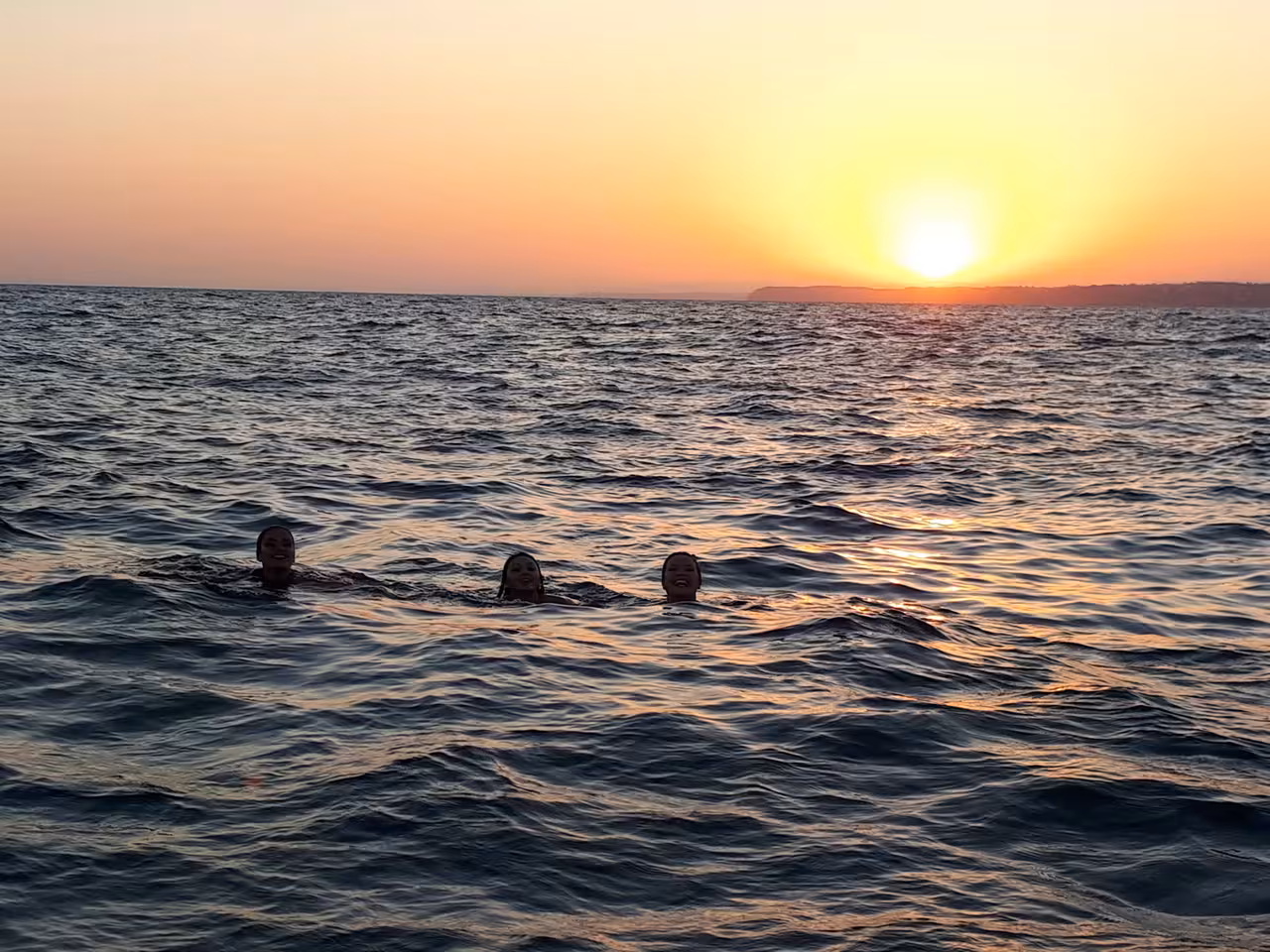 Swimmers in the Atlantic at sunset near Lagos, Algarve, during a Ponta da Piedade sunset cruise experience