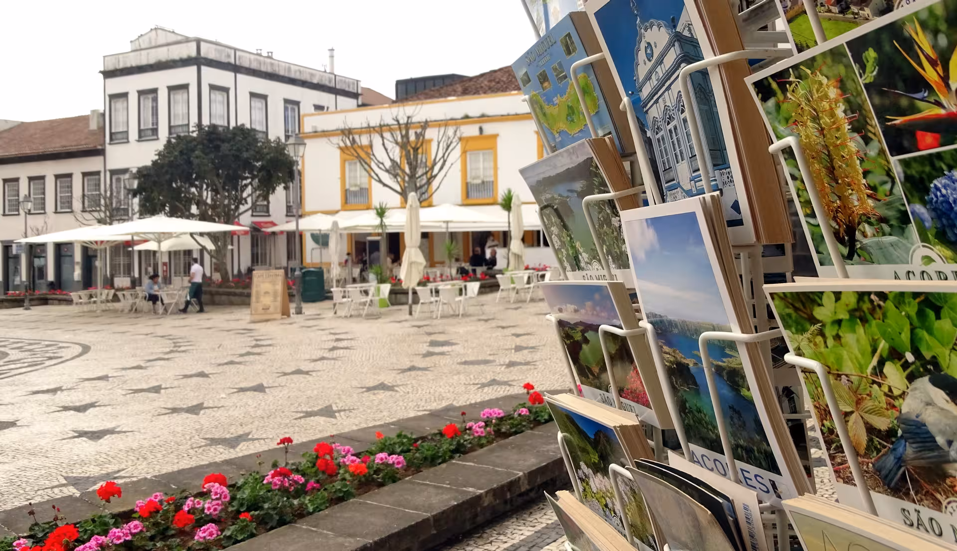 Postcard stand in Ponta Delgada square with mosaic pavement, ideal stop on half-day walking tour Azores