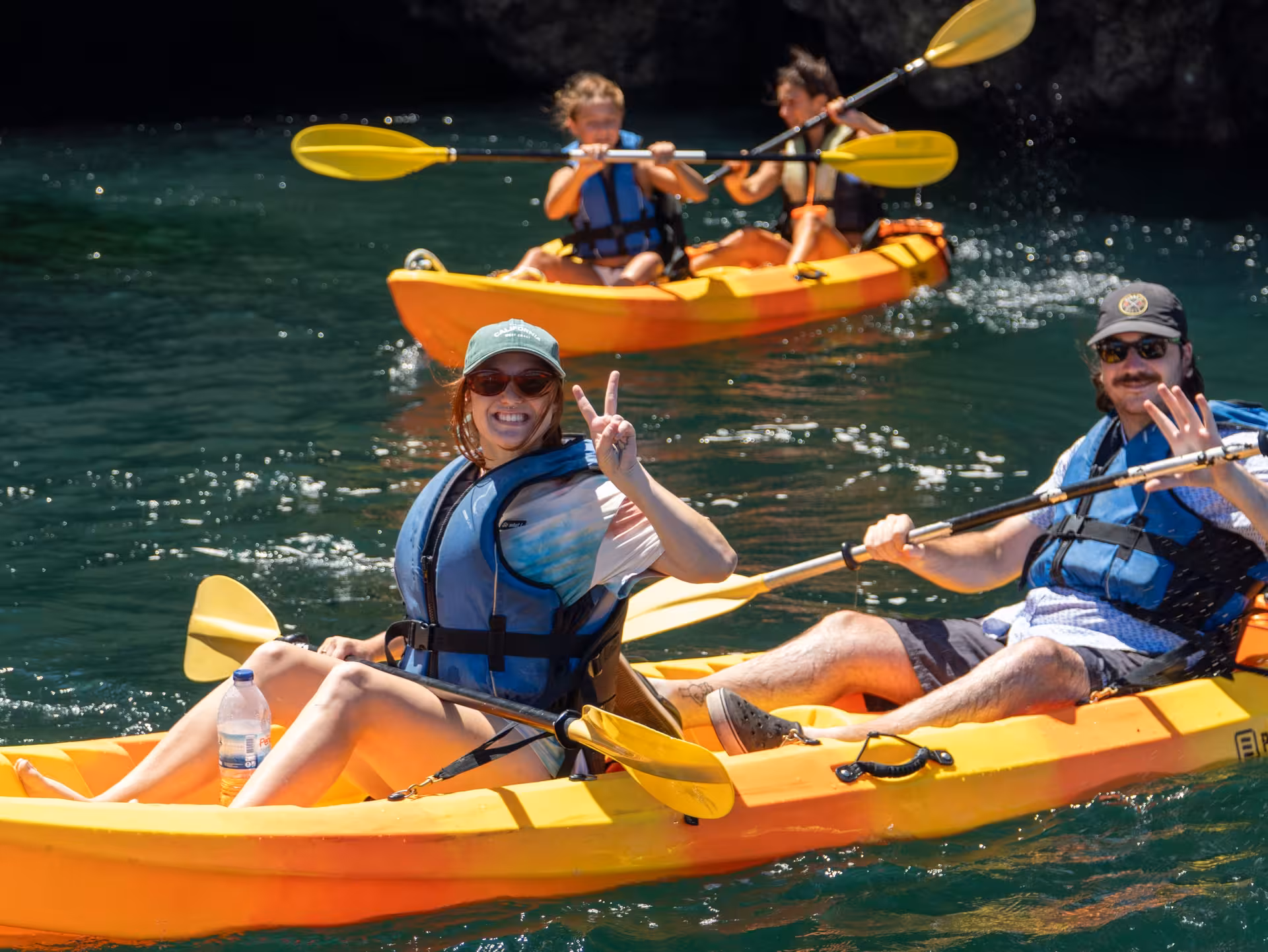 Happy tourists in life jackets enjoying a guided sea kayak tour at Ponta da Piedade rocky coastline in Lagos Portugal