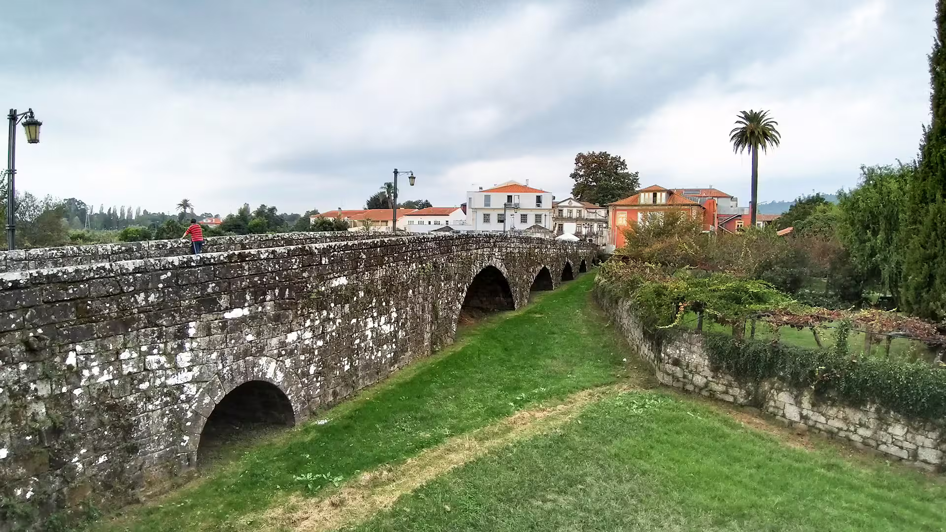 Scenic view of historic Ponte de Lima bridge with lush greenery, perfect for a private tour in Portugal's Vinho Verde region.